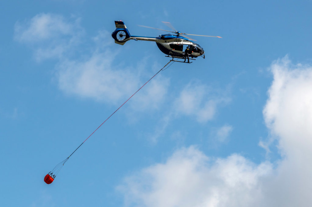 Polizeihubschrauber transportiert einen der neuen Löschwasserbehälter zur Bekämpfunf von Wald- und Flurbränden