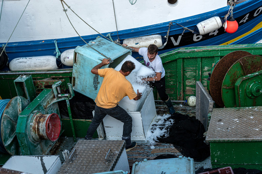 Ein Fischtrawler wird im Fischereihafen von St. Guénolé im Westen der Bretagne mit Eis zur Kühlung des Fangs beladen