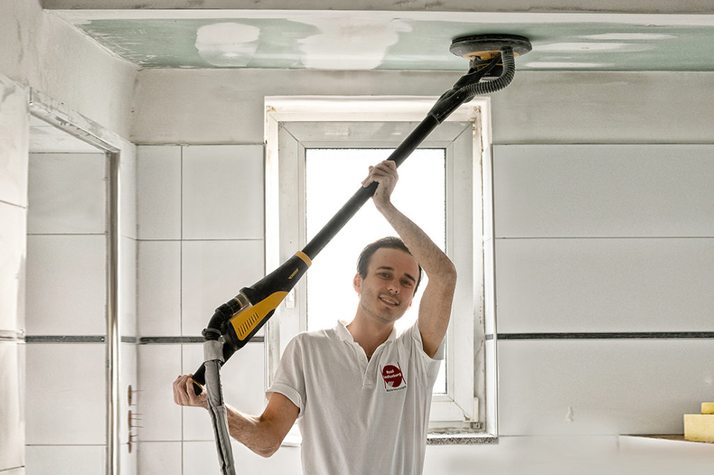 Handwerker schleift die Decke ab und bereitet sie für die Farbe vor.