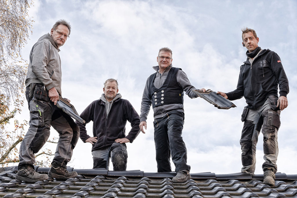 Teamfoto eines Dachdecker-Handwerksunternehmens auf dem Dach